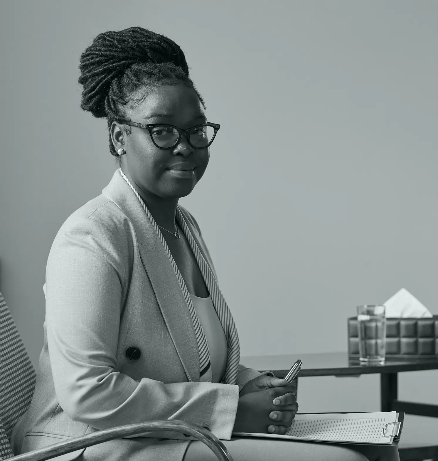 psychologist sitting facing the camera and holding a clipboard